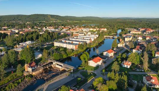 Utsikt över en stad med flod, grönområden och bostadshus i dagsljus.