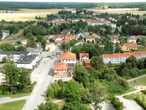 En vy över en bostadsområde med villor, träd och öppna landskap.